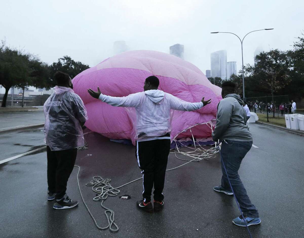 Jeremy Barker, 19, from left, Jacoby Randle, 16, and Lloyd Simon, 17, help raise up a pink ribbon hot air balloon before the Susan G. Komen Race for the Cure on Jan. 27, 2018, in Houston. The event, which is traditionally in October, was rescheduled because of Harvey.