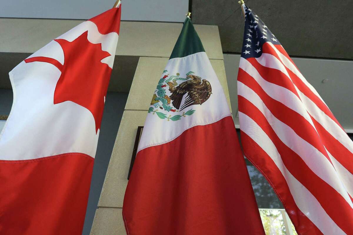 (FILES) Esta fotografía tomada el 24 de septiembre de 2017, muestra las banderas canadiense, mexicana y estadounidense en el lobby donde se llevó a cabo la tercer ronda de negociaciones en Ottawa, Ontario. Los tres países han eliminado los aranceles mutuos a diferentes productos que mantuvieron por varios meses.