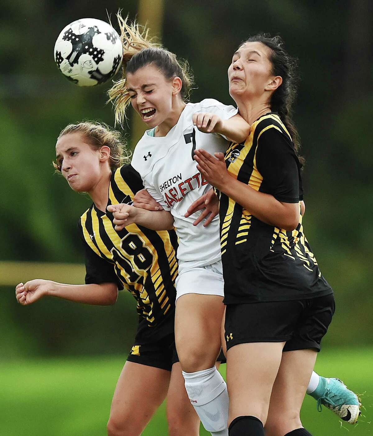 Shelton’s Devan Wildman wins a header during a battle against Amity’s Nicole Grosso (18) and Kayla Morgan on Tuesday.