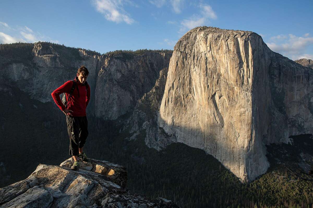 Climber Alex Honnold stands above Yosemite Valley with El Capitan in background. His ropeless climb of El Capitan in 2017 helped vault ball-wall climbing at Yosemite.