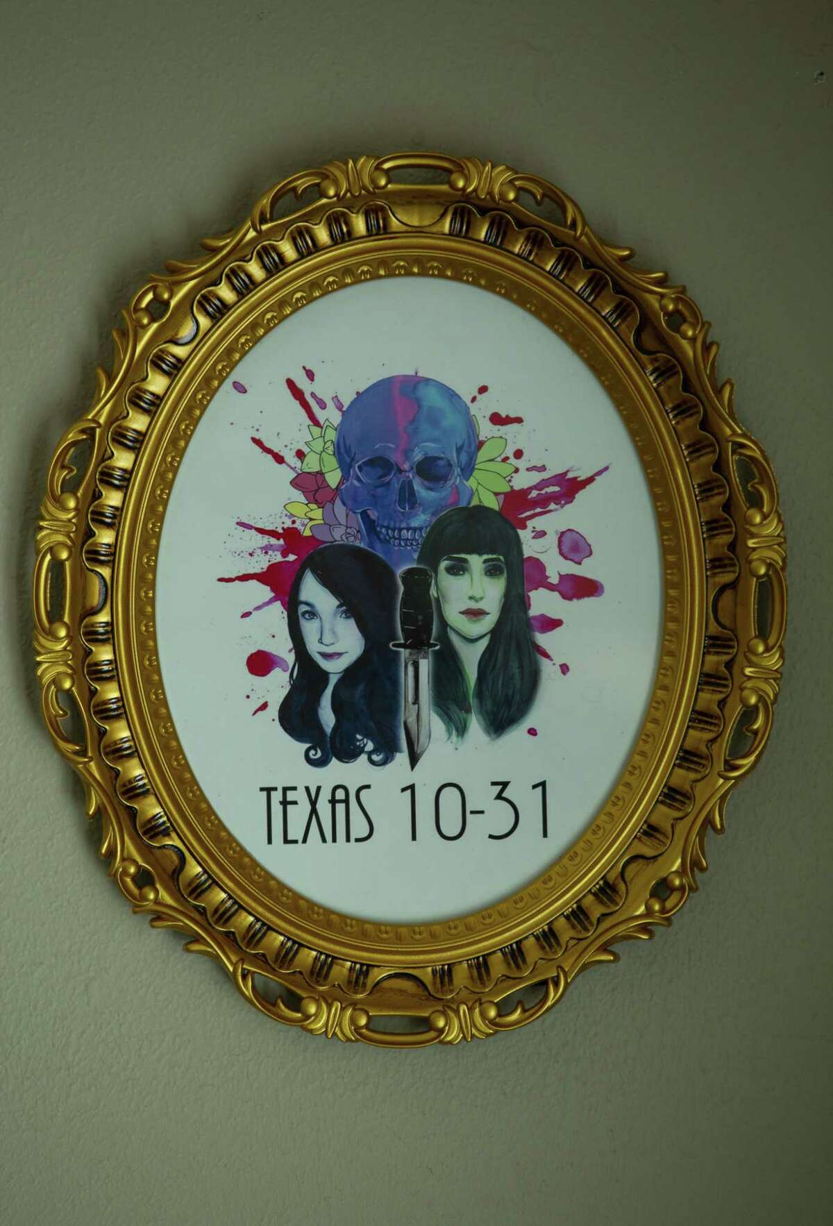 The logo that an artist created for the true-crime podcast, Texas 10-31, hangs on the wall in the room in Cassie Cooper’s Houston home where they record.