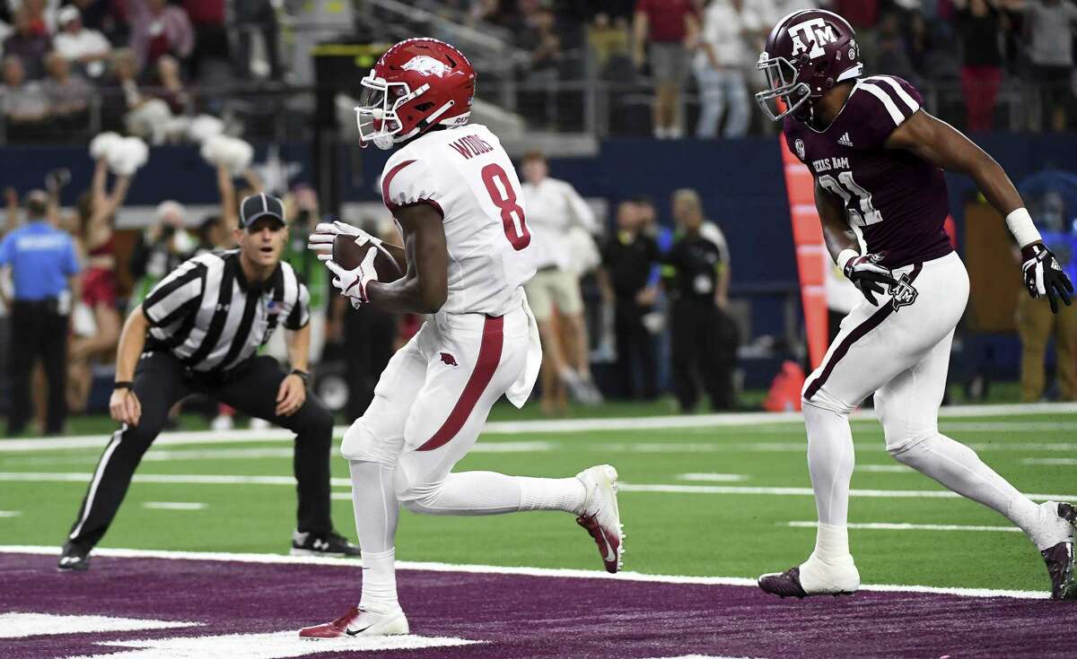 Arkansas wide receiver Michael Woods (8) crosses the goal line ahead of Texas A&M defensive back Charles Oliver (21) on a touchdown reception in the fourth quarter of an NCAA college football game, Saturday in Arlington, Texas.