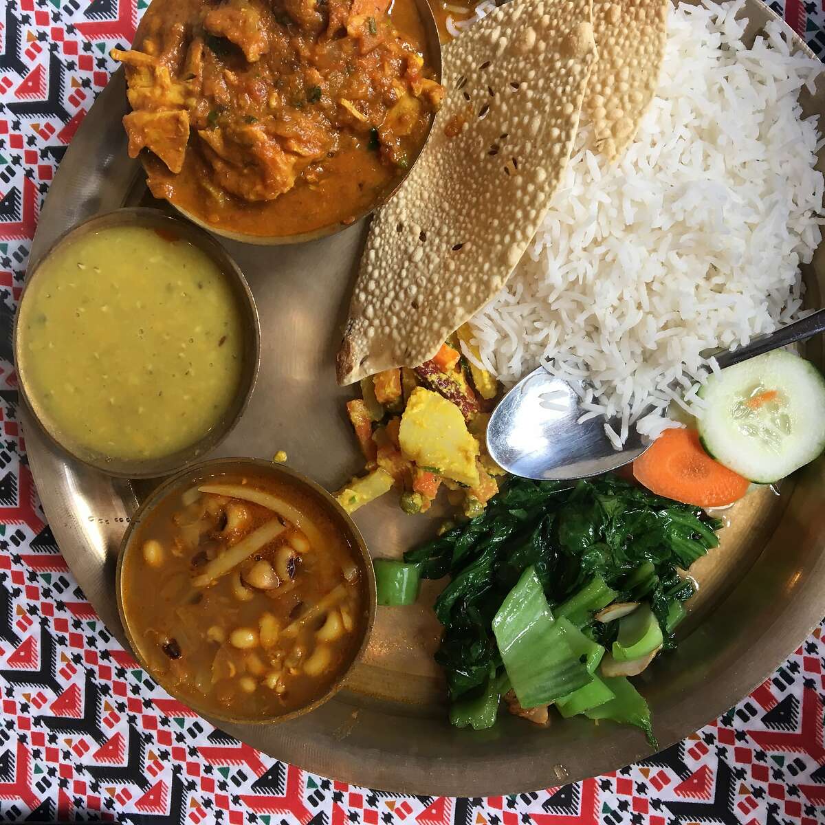 Red Chilli, a resataurant in San Francisco's Tenderloin neighborhood, serves a Nepalese thali with chicken curry, lentils, sauteed mustard greens, potatoes with bamboo shoots and black-eyed peas, and pickle.
