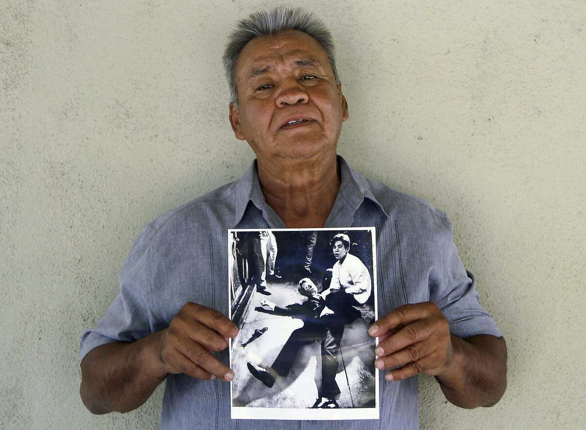 This photo provided by STORYCORPS shows Juan Romero holding a Los Angeles Times photograph that shows Romero with Sen. Robert F. Kennedy at the Ambassador hotel in Los Angeles moments after Kennedy was shot. The Los Angeles Times reported Thursday, Oct. 4, 2018, that Romero died Monday in Modesto, California, at age 68. Romero was a busboy in June 1968 when Kennedy walked through the Ambassador Hotel kitchen after his victory in the California presidential primary and an assassin shot him in the head. He held the mortally wounded Kennedy as he lay on the ground, struggling to keep the senator's bleeding head from hitting the floor. (Jud Esty-Kendall/STORYCORPS via AP)