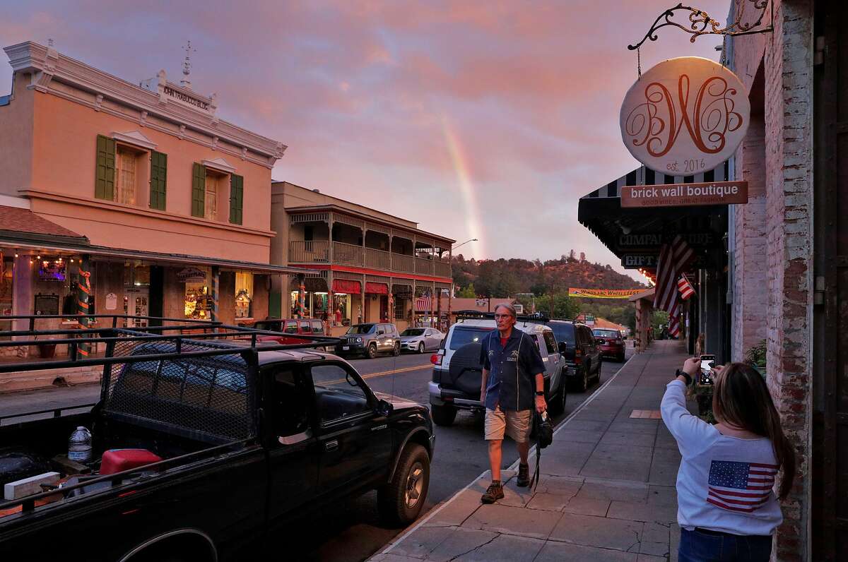 Nadean Andrade takes a photo of a rainbow in downtown Mariposa, Calif., on Wednesday, October 3, 2018. The tourist town, still reeling from the loss of business due to fires, is now also dealing with the effects of the government shutdown and having a number of its residents — many of whom work for Yosemite — not receiving pay.