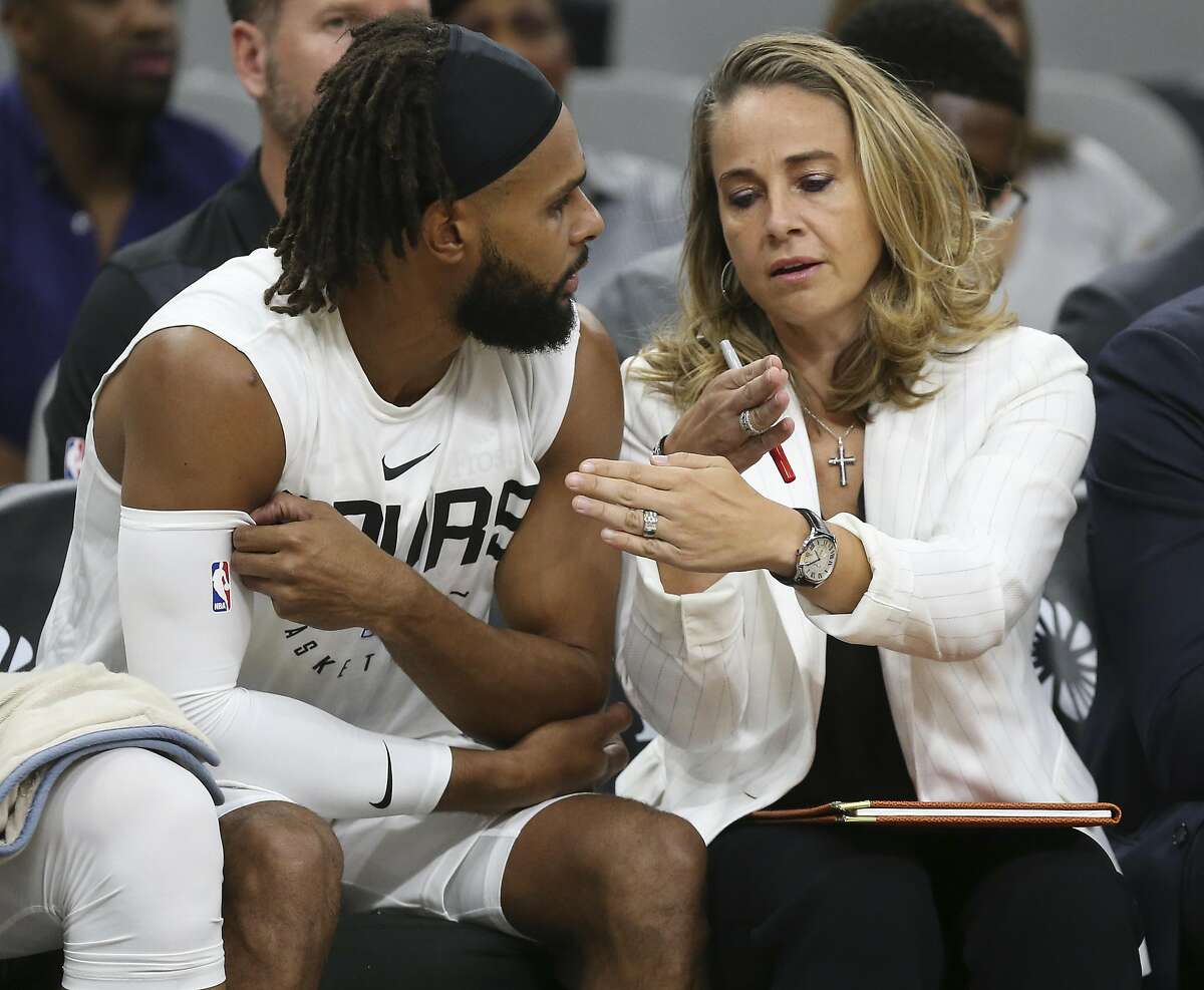 San Antonio Spurs assistant coach Becky Hammon talks with Patty Mills on the bench during the first half against the Miami Heat at the AT&T Center, Sunday, Sept. 30, 2018.