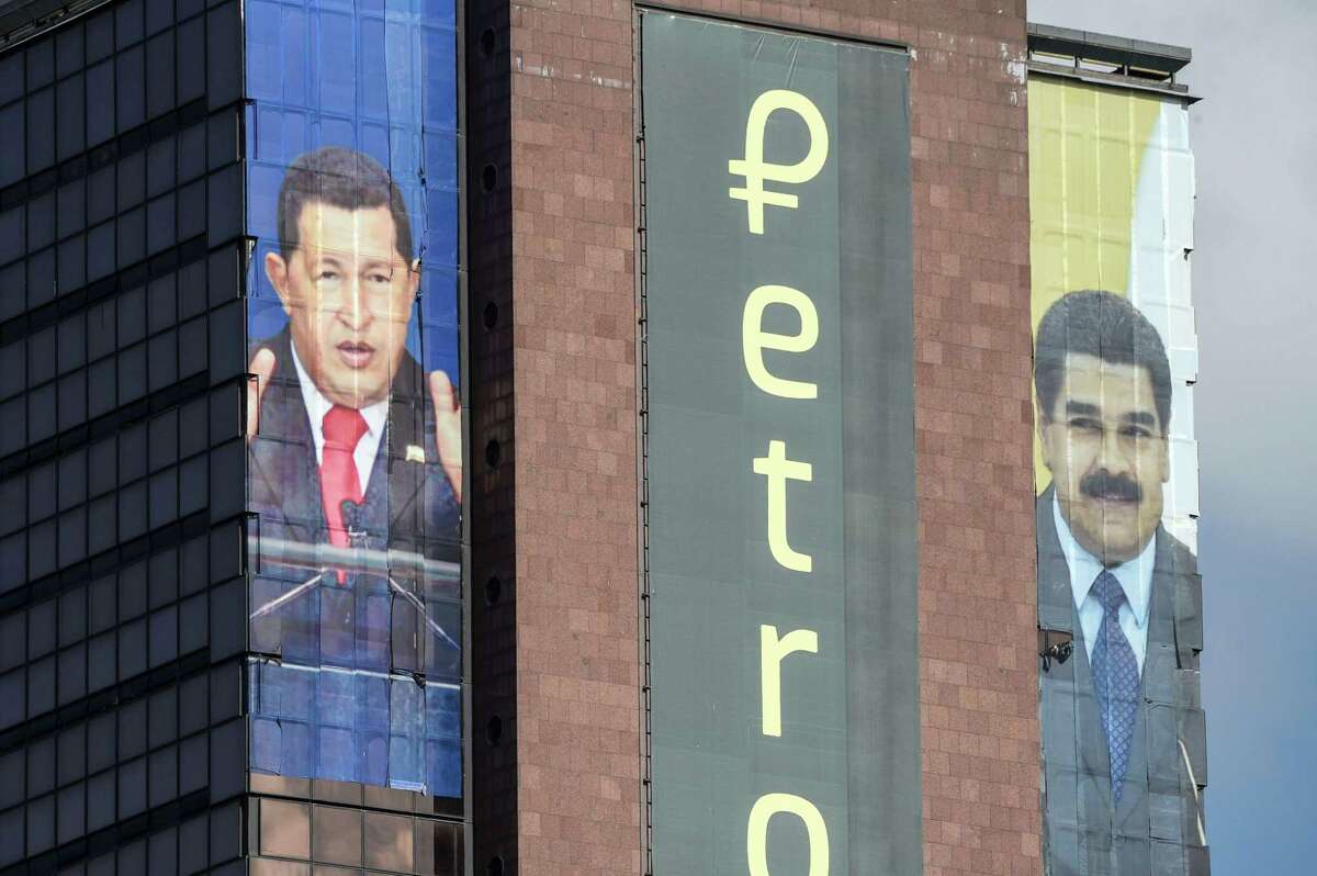 The logo of the "Petro" is displayed next to images of Venezuelan late President Hugo Chavez (L) and Venezuelan President Nicolas Maduro in a building in downtown Caracas, on September 21, 2018. - Six months after Venezuelan cryptocurrency petro, with which the government of Maduro seeks to evade financial sanctions from the US, started selling to the public, it still can not be exchangeable for money, goods or other cryptocurrencies as the bitcoin. (Photo by Federico PARRA / AFP)FEDERICO PARRA/AFP/Getty Images
