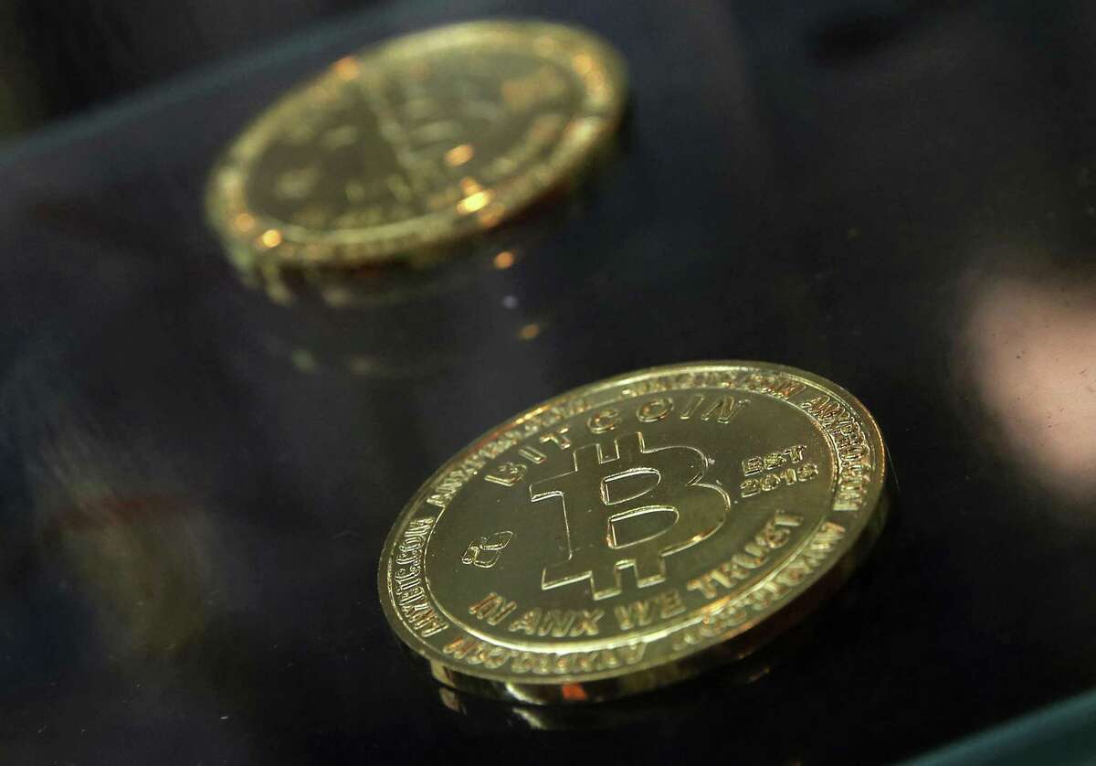 FILE- In this Dec. 8, 2017, file photo, coins are displayed next to a Bitcoin ATM in Hong Kong. British lawmakers are urging regulation for cryptocurrencies such as bitcoin in a report that describes the current situation as the "Wild West." In a report Wednesday, Sept. 19, 2018 on digital currencies, Parliament's Treasury Committee called for regulations to protect consumers and prevent money laundering. (AP Photo/Kin Cheung, File)