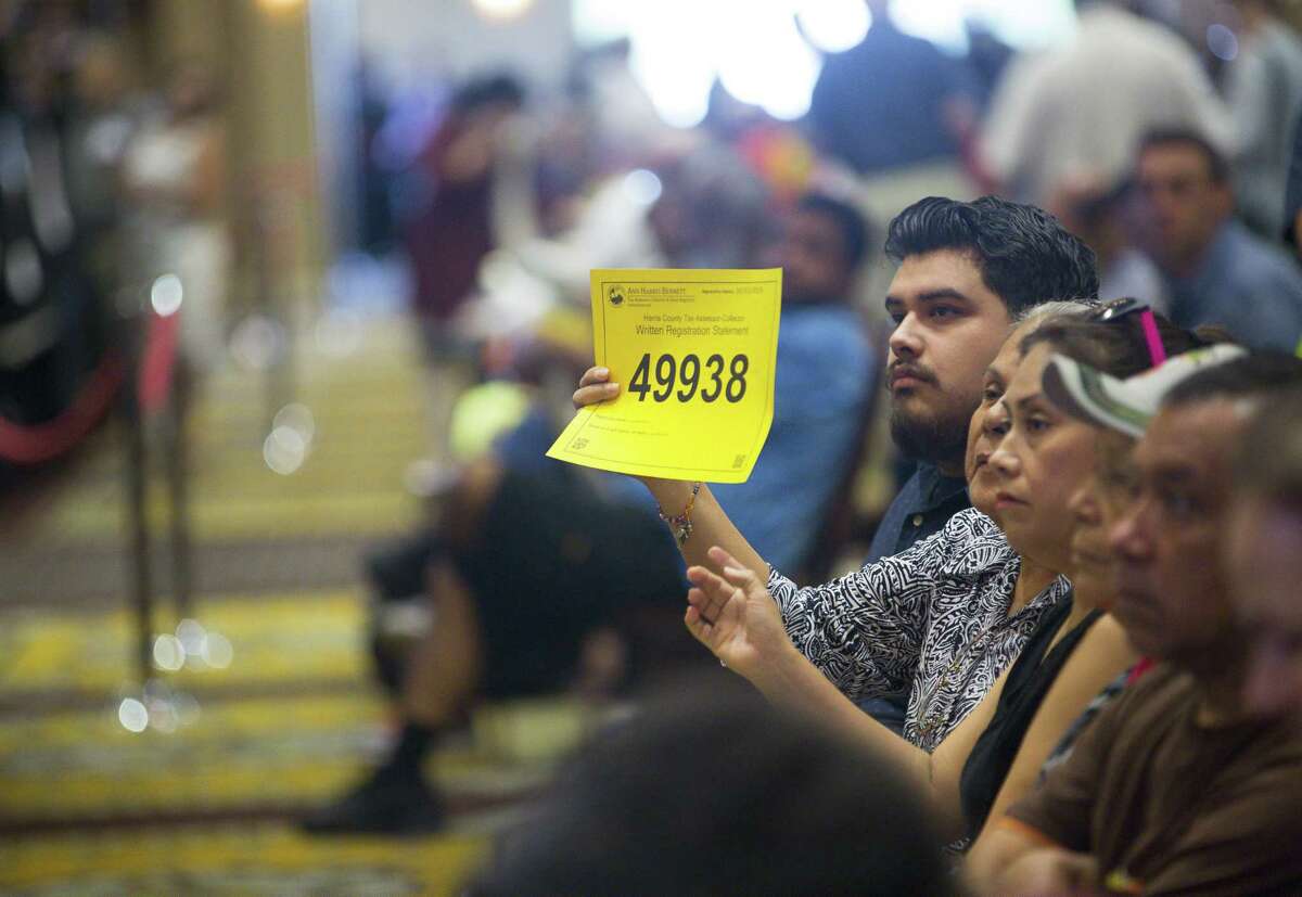 A bidder raises their number during the monthly foreclosure auction hosted by Harris County at the Bayou City Events Center, Tuesday, Oct. 2, 2018 in Houston. Delinquent tax sales are divided up by constable precincts during the monthly foreclosure auction. CONTINUE to see what areas had the most homes flooded by Harvey. 