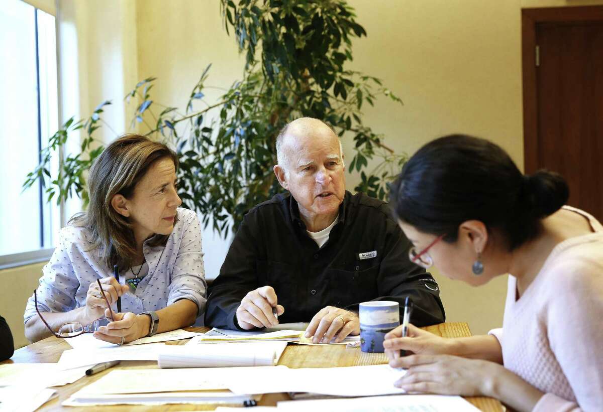 On Sept. 30, 21018, Gov. Jerry Brown reviews a measure with his wife, Anne Gust Brown, left, and his deputy legislative secretary, Graciela Castillo-Krings, right, at his Capitol office, in Sacramento, Calif. Brown signed into law that day legislation requiring public companies based in California have at least one woman on their boards of directors.