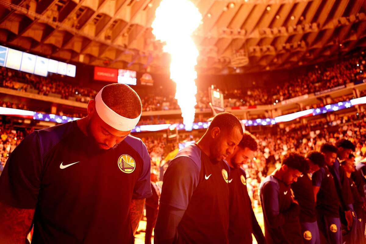 From left: Golden State Warriors center DeMarcus Cousins at his first NBA game with the Warriors stands during the national anthem with guard Andre Iguodala (9) before an NBA preseason game between the Golden State Warriors and Minnesota Timberwolves at Oracle Arena on Saturday, Sept. 29, 2018, in Oakland, Calif. Cousins did not play due to a current injury.