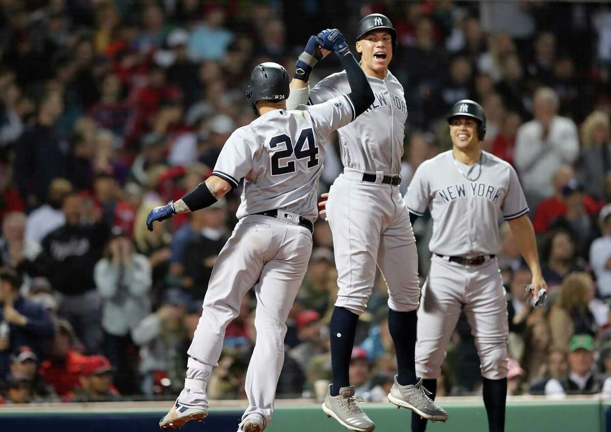BOSTON, MA - OCTOBER 06: Gary Sanchez #24 and Aaron Judge #99 of the New York Yankees celebrate after Sanchez hit a three-run home run as teammate Giancarlo Stanton #27 watches during the seventh inning of Game Two of the American League Division Series against the Boston Red Sox at Fenway Park on October 6, 2018 in Boston, Massachusetts. (Photo by Elsa/Getty Images)