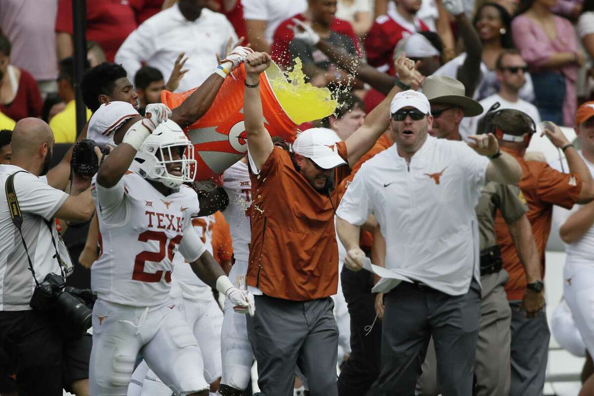 Texas Longhorns Head Coach Tom Herman (center in orange) celebrates just before being doused with liquid after an NCAA college football game against the Oklahoma Sooners, Saturday in Dallas, Texas.