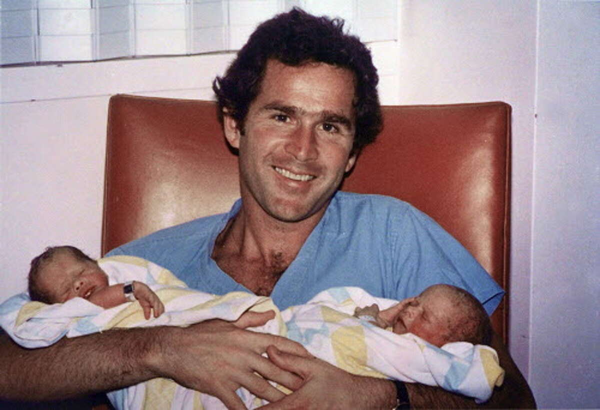 George W. Bush, seen here in a 1981 file photo in Dallas, holds his twin daughters, Barbara and Jenna. 