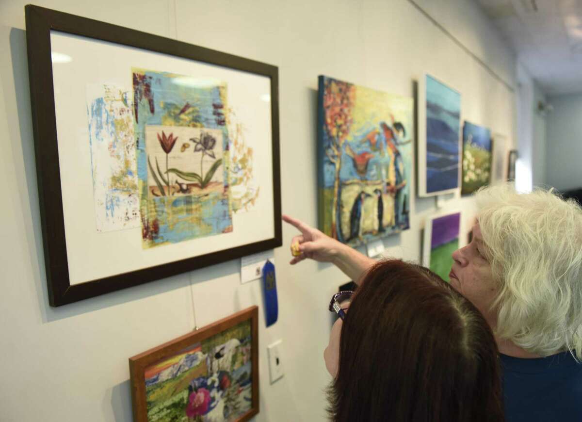 Artist Carolyn Lyngholm, right, shows her first-place mixed media work "Floral Fantasy" to Jeanette Briggs at the opening reception of the Art Society of Old Greenwich's Autumn Members Show at the Garden Education Center in the Cos Cob section of Greenwich, Conn. Sunday, Oct. 7, 2018. Works in a variety of mediums were presented at the show, judged by UConn Art & Art History Department Head John Richardson. The art will be on display until Oct. 28.