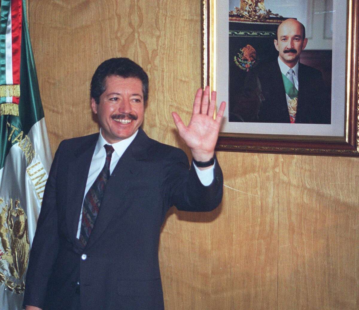 FILE--Secretary of Social Development Luis Donaldo Colosio greets reporters in his Mexico City office Nov. 28, 1993 after he was named as the ruling Institutional Revolutionary Party's presidential candidate. A Mexican flag and a portrait of Mexican President Carolos Salinas de Gortari are seen in the background. Special investigator Luis Raul Gonzalez of Mexico Attorney General's office gave his final report Friday, Oct. 20, 2000 on the March 26, 1994 assassination of then-presidential candidate Luis Colosio. The four-year investigation into the Tijuana killing of the PRI candidate concluded that he was killed by a lone gunman, Mario Aburto, now in prison. (AP Photo/Carolos Taboada)