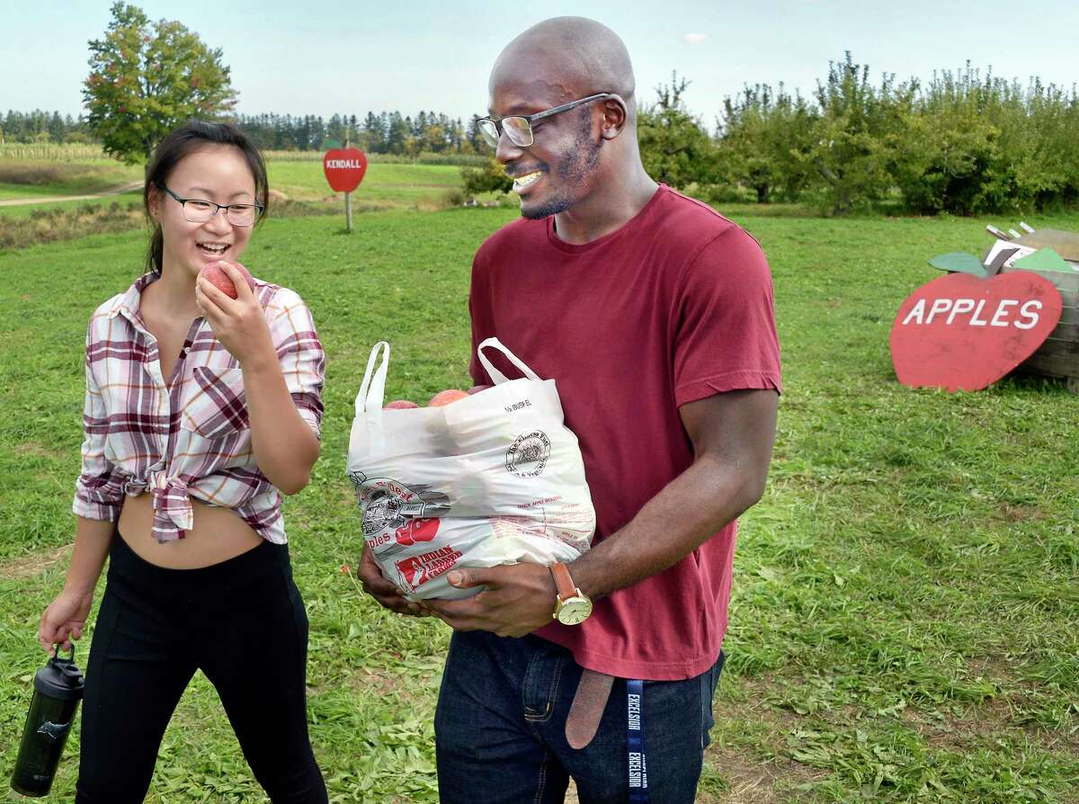 Emily Fitzgerald, left, of Springvale, Maine, samples an apple as she and Clifton Amponsah of Colonie pick their own at Indian Ladder Farms Tuesday Oct. 9, 2018 in Altamont, NY. (John Carl D'Annibale/Times Union)