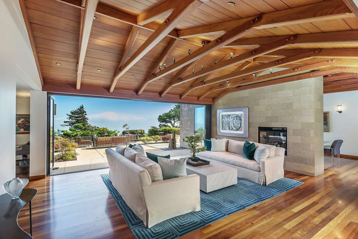 The great room at 93 Cloud View Road in Sausalito features a vaulted ceiling and stone wall with a gas fireplace.