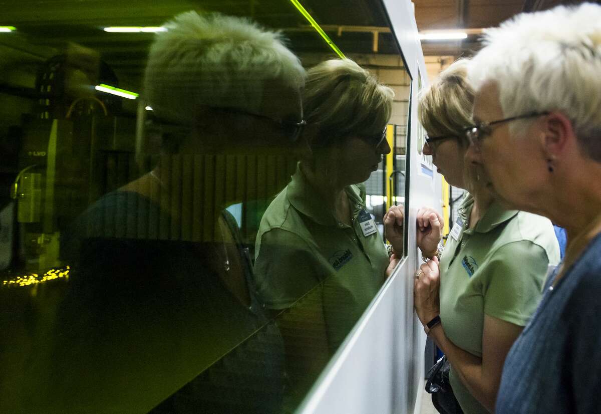 Tina Lewis, right, and Diane Middleton, second from right, both of the Midland Area Chamber of Commerce, peer through a window at the brand new Phoenix laser at Case Systems and BOSTONtec during a ribbon cutting event Tuesday, Oct. 9, 2018 at the facility in Midland. (Katy Kildee/kkildee@mdn.net)