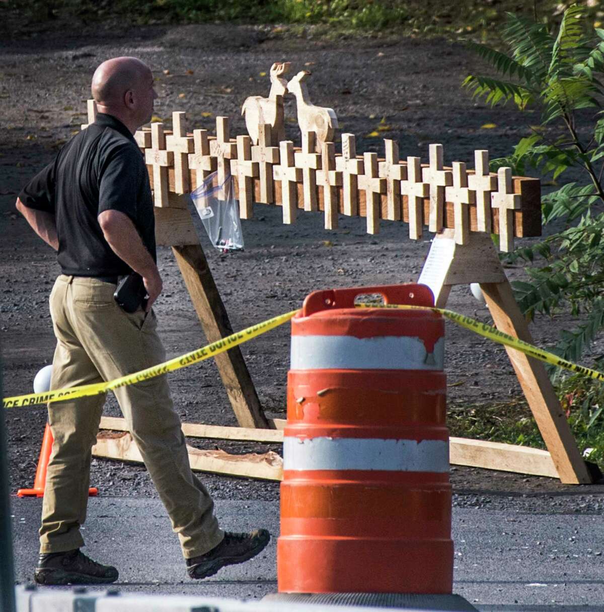 Forensics Investigator from the New York State Police walks past a makeshift memorial at the site of the limousine accident Near the Apple Barrell tourist spot Tuesday Tuesday Oct.8, 2018 in Schoharie, N.Y. that took the lives of twenty people last weekend. (Skip Dickstein/Times Union)