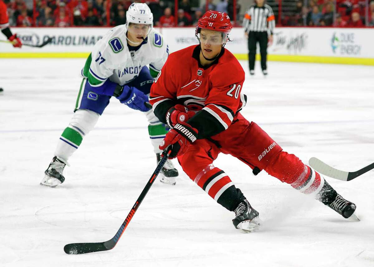 Carolina Hurricanes' Sebastian Aho (20) gathers in the puck in front of Vancouver Canucks' Nikolay Goldobin (77) during the second period of an NHL hockey game, Tuesday, Oct. 9, 2018, in Raleigh, N.C. (AP Photo/Karl B DeBlaker)