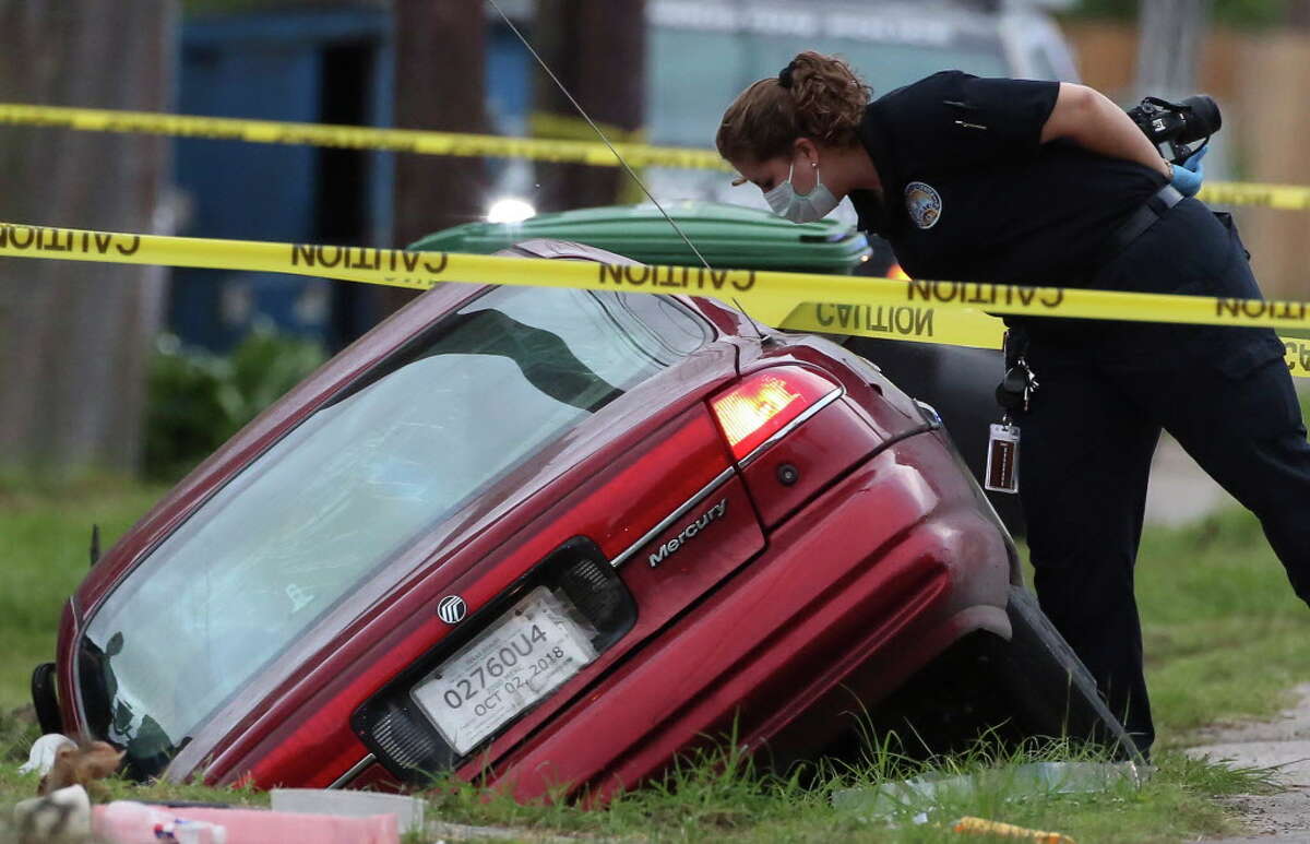 HPD and Houston Forensic Science Center authorities investigate a homicide scene where an adult female driver died of injuries in a red car in the ditch of 6600 block of Fairway Drive on Wednesday, Oct. 10, 2018, in Houston. A male suspect who was riding in the car with the female driver fled the scene after a domestic dispute started in the moving car.