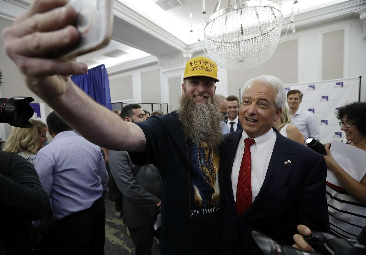 ADVANCE FOR RELEASE SATURDAY, OCT. 6, 2018, AND THEREAFTER - FILE - In this June 5, 2018, file photo, Republican gubernatorial candidate John Cox, right, stands with a supporter for a picture during a Republican election party in San Diego. Cox, a businessman living in the San Diego area, is running against Lt. Gov. Gavin Newsom to replace California Gov. Jerry Brown. (AP Photo/Gregory Bull, File)