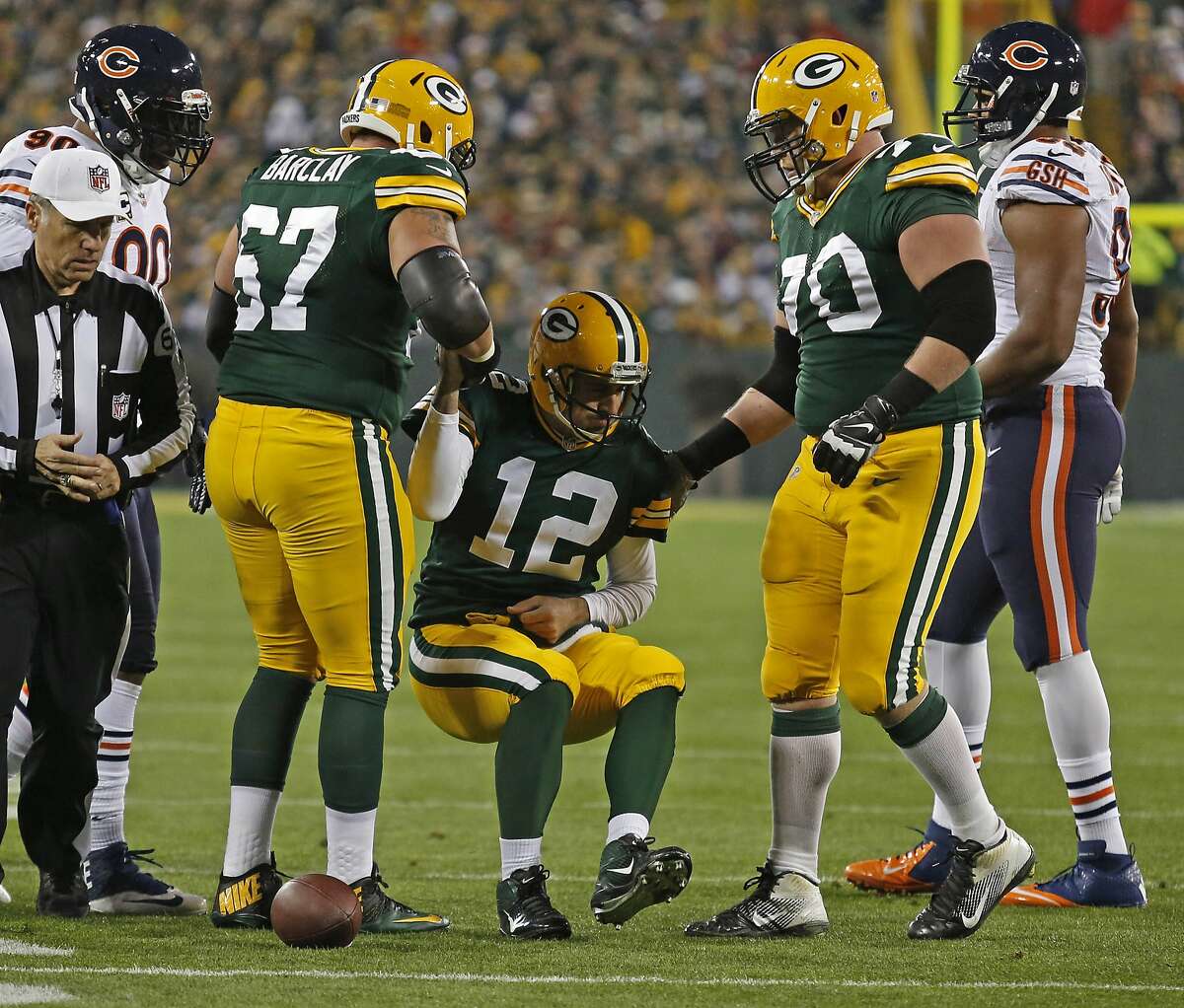 Green Bay Packers quarterback Aaron Rodgers is helped up by teammates tackle Don Barclay (67) and guard T.J. Lang (70) after being injured on a play by Chicago Bears defensive end Shea McClellin during an NFL football game Monday, Nov. 4, 2013, in Green Bay, Wis. (AP Photo/Matt Ludtke)