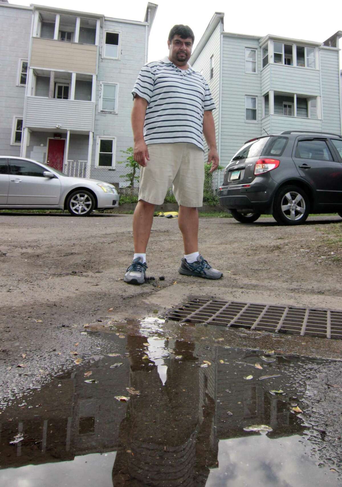 Wallace Court resident Pedro Quiroga stands near a drain that constantly backs up and floods the whole street in Bridgeport, Conn., on Tuesday Oct. 9, 2018. Many homes in the neighborhood were damaged by the flooding, including Quiroga's, after a heavy rainstorm on Tuesday Oct. 2, 2018.