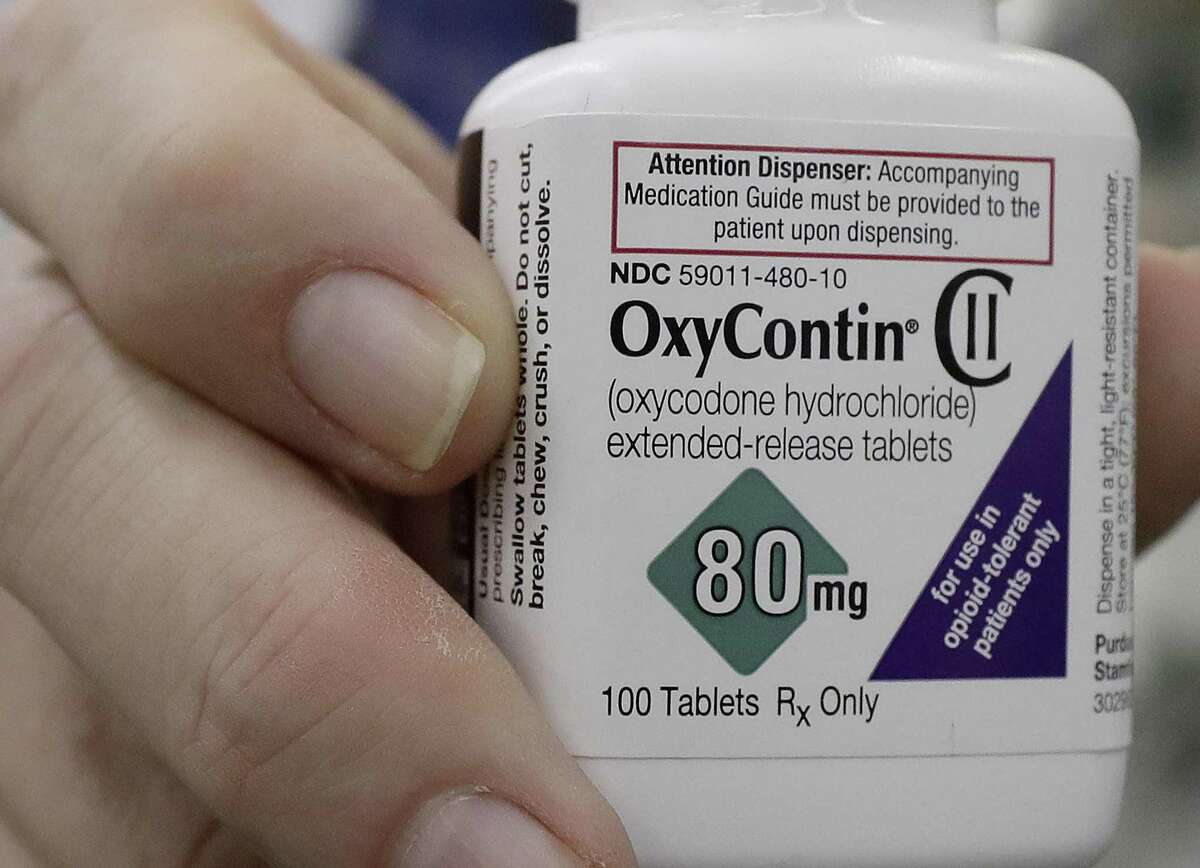 FILE - In this April 2, 2018, file photo, pharmacist Steve Protzel poses for photos holding a bottle of OxyContin at Daniel's Pharmacy in San Francisco. The state of Colorado is suing Purdue Pharma, the maker of OxyContin, for manipulating Colorado doctors into prescribing the powerful pain medication and failing to inform state or federal authorities about suspicious orders or prescribing patterns. Purdue denies the allegations. (AP Photo/Jeff Chiu, File)
