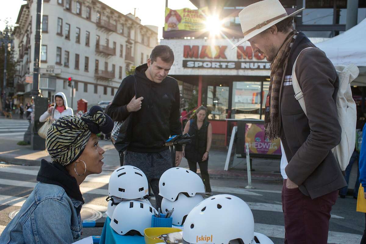 Taylour Miller-Fisher, Skip outreach team representative, talks to Leigh Christie (right) and Allen Saakyan at the demonstration booth of Skip, a scooter rental company, at the Castro Farmers' Market. Wednesday, October 10, 2018 in San Francisco, Calif.