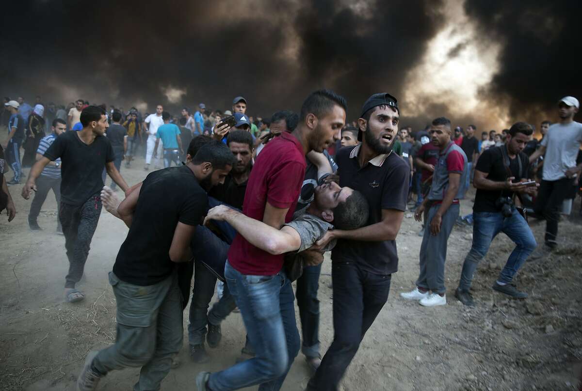 Palestinian protesters evacuate a wounded man was shot by Israeli troops during a protest at the Gaza Strip's border with Israel, Friday, Oct. 12, 2018. (AP Photo/Khalil Hamra)