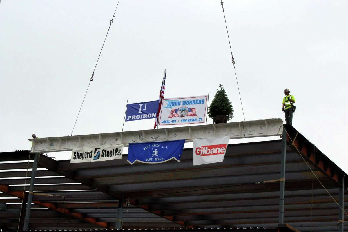 A signed I-beam is hoisted by a large crane and set by two iron workers atop West Haven High School's future media center during a "topping-off" ceremony on Thursday, Oct. 11, 2018 to celebrate completion of the steel framework for the addition portion of the school's $130 million reconstruction and renovation project.