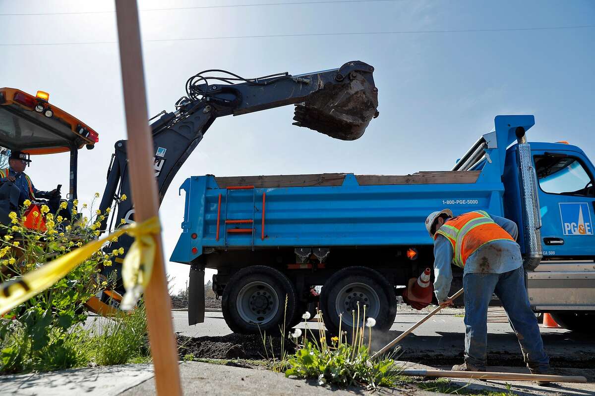 A PG&E worker moves spilled dirt as a trencher digs a trench as PG&E crews and subcontractors began prepping for underground utility lines in the Coffey Park neighborhood of Santa Rosa, Calif., on Monday, April 2, 2018. The neighborhood was devastated by fire in October as dozens of residents perished when thousands of homes in the region were destroyed in the North Bay fires in the region.
