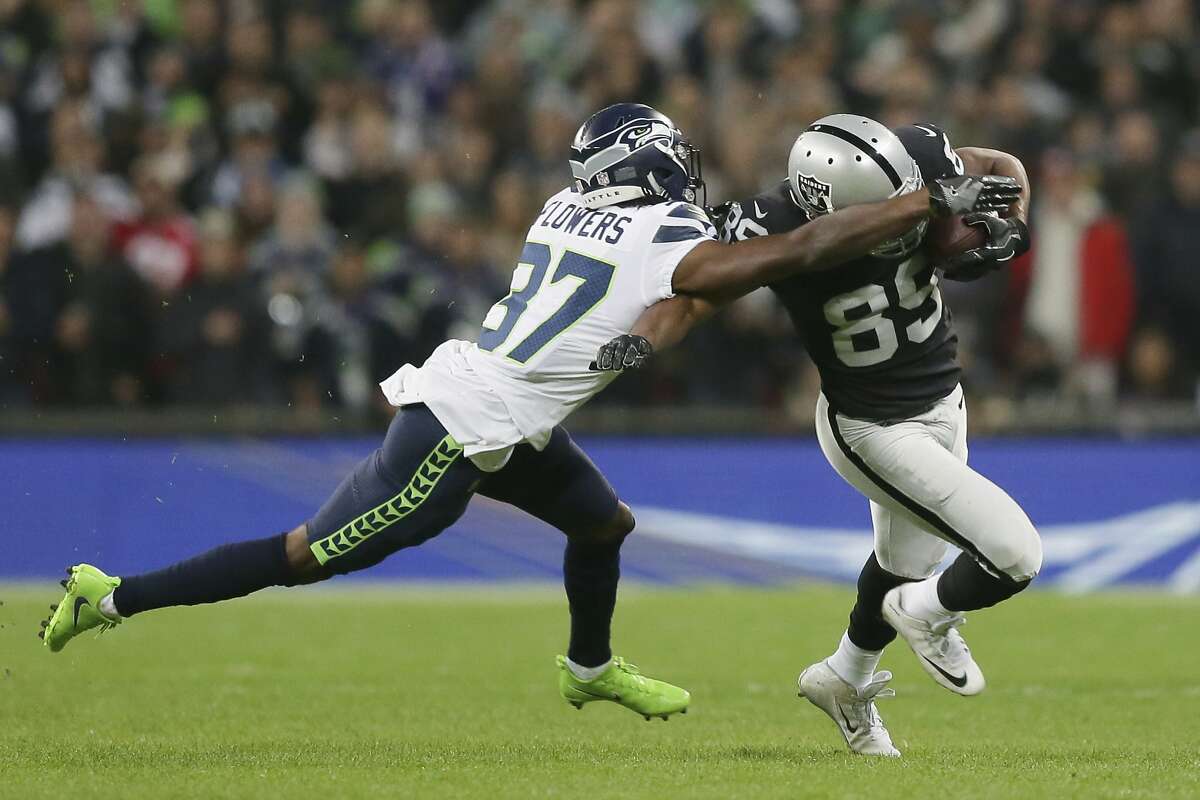 Seattle Seahawks cornerback Tre Flowers (37) tackles Oakland Raiders wide receiver Amari Cooper (89) during the first half of an NFL football game at Wembley stadium in London, Sunday, Oct. 14, 2018. (AP Photo/Tim Ireland)