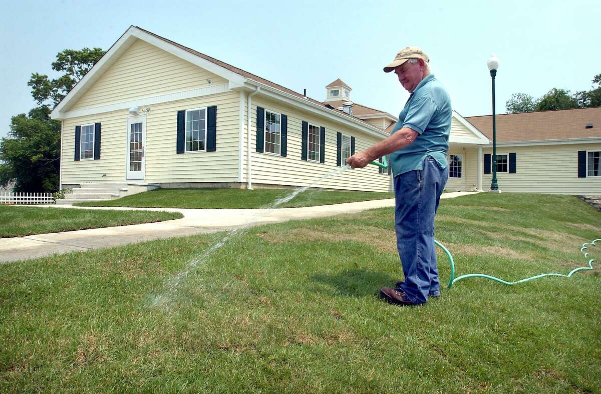 Joe Muldoon waters sod in front of new residential facilities at the Boys & Girls Village complex in Milford in 2004.