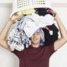 Frustrated young man with full of clothes on his head. Laundry time