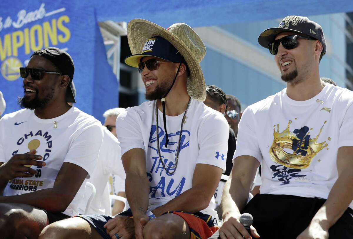 Golden State Warriors' Kevin Durant, left, Stephen Curry, center, and Klay Thompson smiles during a parade after winning the NBA basketball championship Tuesday, June 12, 2018, in Oakland, Calif.
