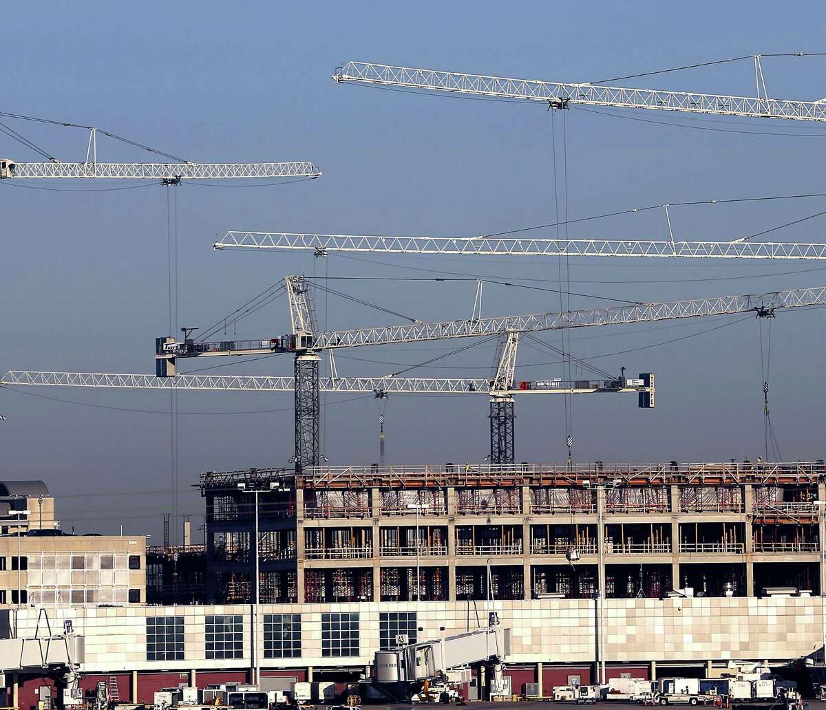 The booms from five tower cranes are seen Wednesday, Dec, 21, 2016 at the San Antonio International Airport as they help construct improvements at the airport, such as a new parking garage.