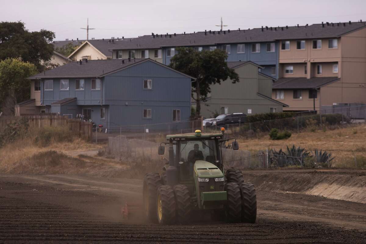 In this Wednesday, Sept. 5, 2018, photo, a tractor plows in a field near apartment buildings in Salinas, Calif. Salinas is an affordable location compared to Silicon Valley, where median home prices are about $1 million, but with a less-wealthy population and a median home price that has ballooned to about $550,000, it's one of the least affordable places in America. (AP Photo/Jae C. Hong)