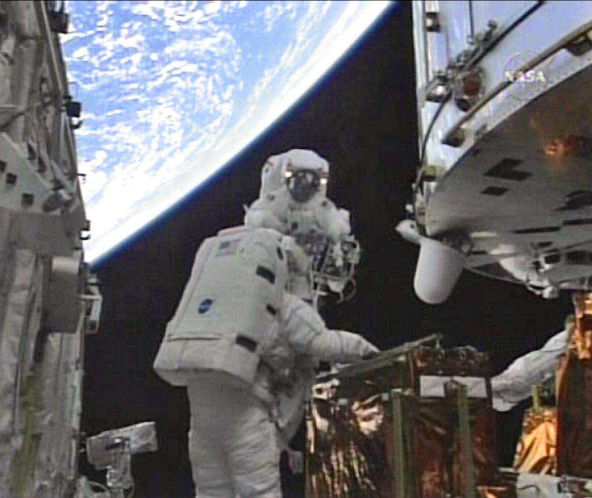 In this image from NASA TV with earth in the background, astronauts John Grunsfeld, rear, and Andrew Feustel work to upgrade the Hubble Space Telescope during a spacewalk on May 18, 2009. This was the fifth and final repair mission for what was then a 19-year-old telescope.
