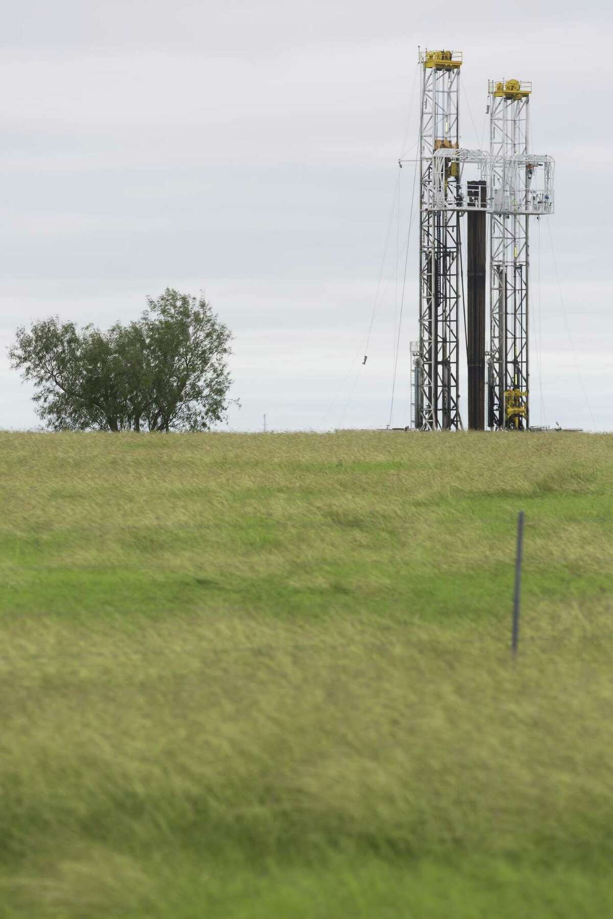A drilling rig rises Wednesday, Oct. 18, 2018 behind a pasture a few miles outside Kenedy in the heart of the Eagle Ford shale oil play.