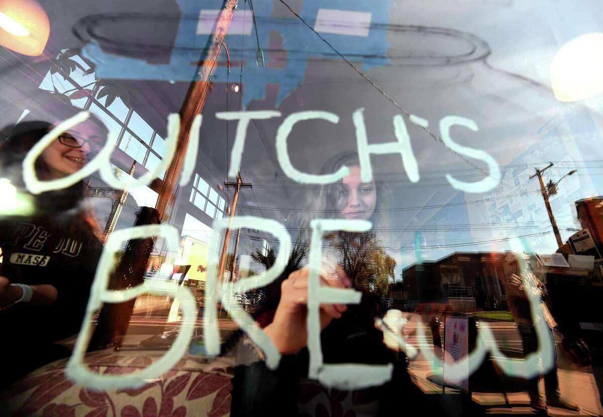 Platt Technical High School sophomore Kaitlyn Madigan paints a Halloween theme on the front window of Cafe Atlantique on River Street in Milford with classmates on October 19, 2018.
