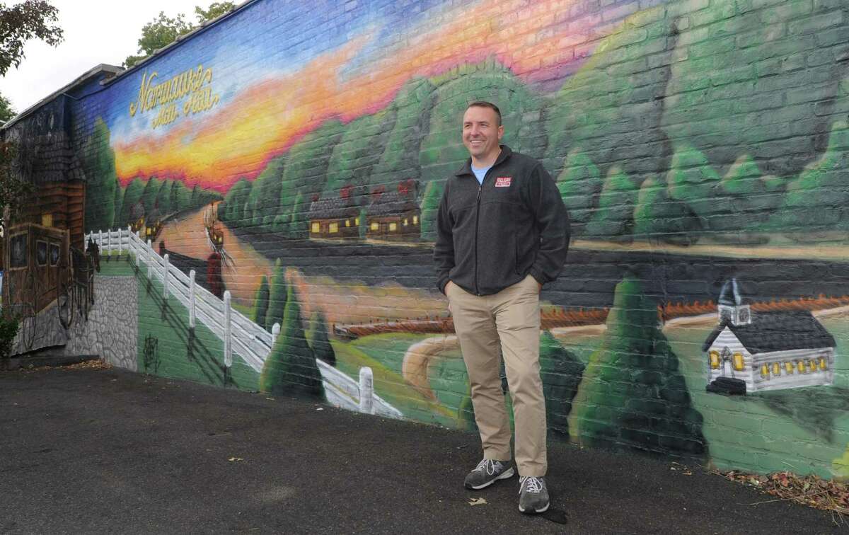 Jason Milligan, owner of Milligan Realty, stands next to the mural he had painted on his building at 97 Wall Street Friday, October 19, 2018, in Norwalk, Conn. The Wall Street Neighborhood Association, to which commercial real-estate developer Jason Milligan belongs, has launched an online petition titled ?‘Save the Wall Art on Wall Street?’ at change.org. The launch comes after Milligan recently had a mural painted on his property at 97 Wall St. and remains under a zoning violation for the mural he had painted on his building at 21 Isaacs St. Milligan, who remains the subject of a lawsuit after purchasing those and other properties within the stalled Wall Street Place development area,