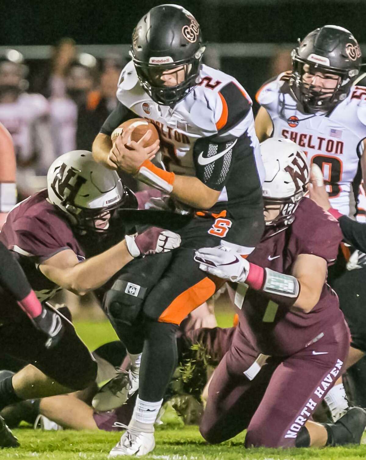 Shelton’s Jake Roberts splits North Haven defenders Luke Maruca, right, and Von DePalma Friday in North Haven.
