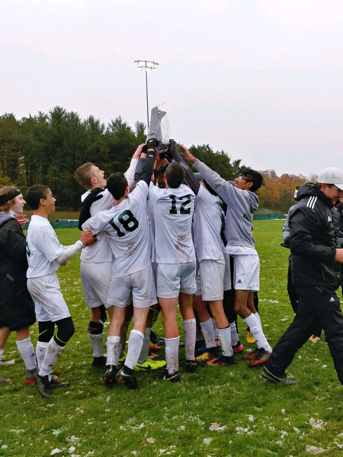 Dow High soccer players lift the district championship trophy on Saturday after beating Traverse City West 4-3 in the district final in Traverse City. (Photo provided)