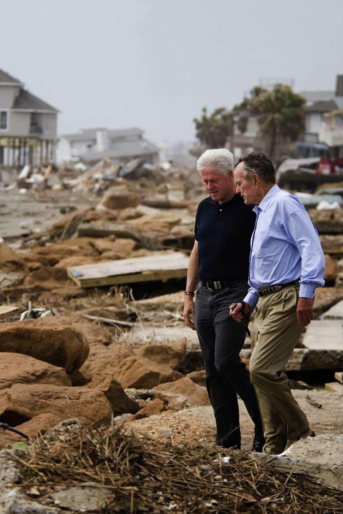 Former U.S. Presidents George H.W. Bush, right, and Bill Clinton walk through debris at Bermuda Beach on Galveston Island as they toured areas affected by Hurricane Ike in this photo from Oct. 14, 2008.