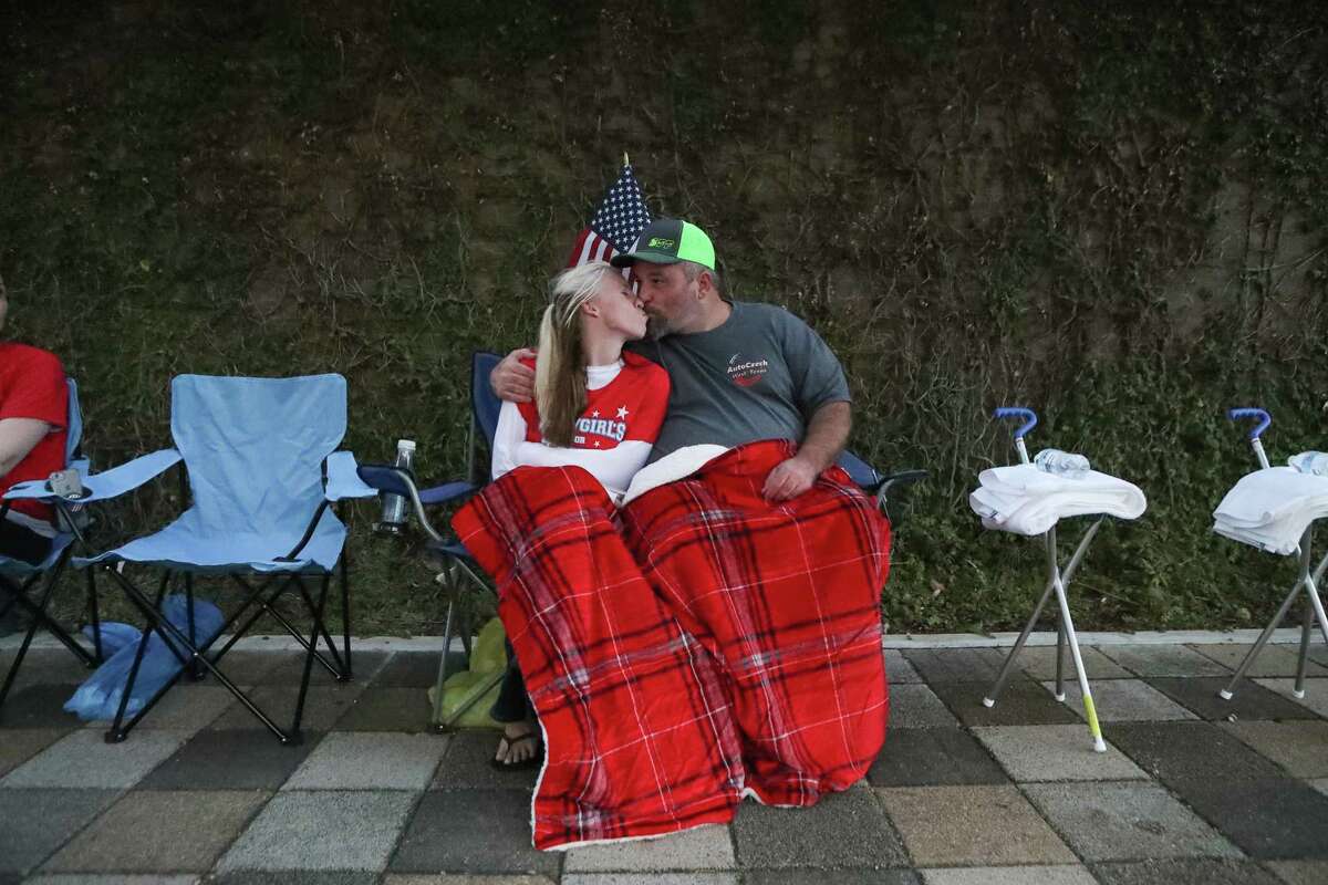 Deejay Miller (left) kisses her fiancée Glenn Collins, Waco, Tx, as they stay warm hours before President Donald Trump's rally Monday night at Toyota Center Sunday, Oct. 21, 2018, in Houston.