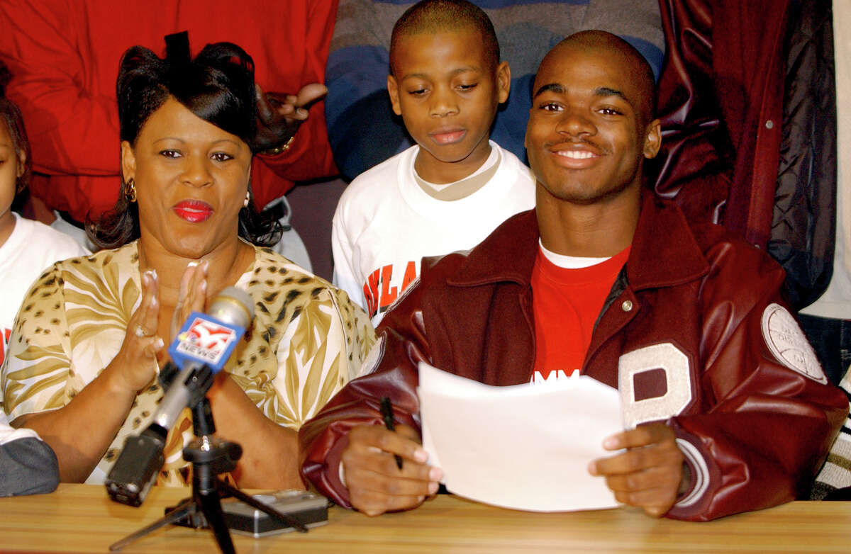 Palestine runnning back Adrian Peterson, right, smiles after signing a national letter of intent to play football for Oklahoma Wednesday, Feb. 4, 2004, in Palestine, Texas. Peterson, who rushed for 2,315 yards and 32 touchdowns in his senior season, is considered one of the top high school recruits in the nation. At left is his mother Bonita Jackson, and at center is his brother, Jaylon Jackson.