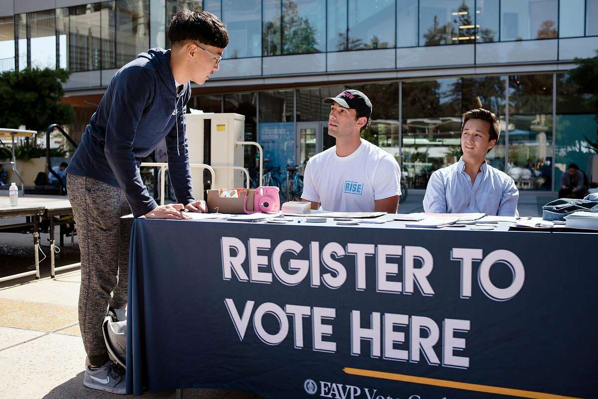 VoteCrew creator and Rise California member Maxwell Lubin, center, and Berkeley City Council candidate Rigel Robinson help Cal student Harry Lee, left, register to vote during a VoteCrew event during National Voter Registration Day on the UC Berkeley campus in Berkeley, Calif., on Tuesday September 25, 2018